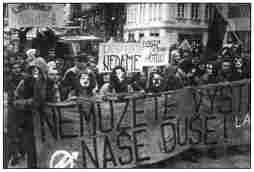 photo shows crowd of angry protesters with black flags and banners.