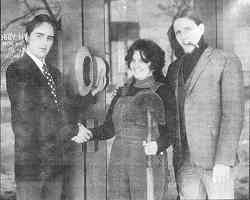 Photo shows two businessmen praising woman, who is holding a broom or mop.