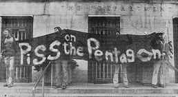 Photo shows 4 men holding a banner in front of the Pentagon; banner reads, "Piss on the Pentagon."