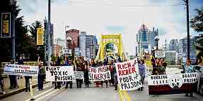 Photo shows street demonstration with many signs, such as "Fight toxic prisons."