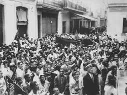 Photo shows a rally with thousands of workers attending, some bearing banners or signs.