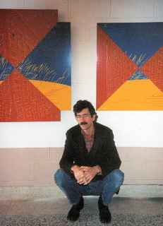 photo shows Paul Schwartz posing before two large paintings