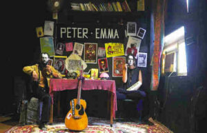 A photo depicts a scene from the operetta "Peter and Emma's Bookcafe." The interior of the cafe is shown with many books. Seated at left is Peter, seated at right is Emma.