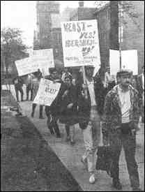 A photo shows an anti-war protest. A sign reads "Keast YES, Hershey NO."