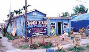 A blue house and large tent. Signs in front yard read, "Common Ground Lower 9th Relief;" "Respect this community;" "You can be involved;" "eminent domain for who?"